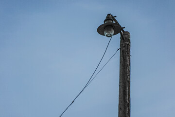 dark silhouette of an old rusty lamp post against dark blue sky in twilight
