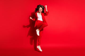 Full length photo of gorgeous young lady jump raise fist wear blazer pants footwear isolated red...