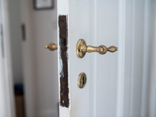White door made of wood with brass handle slightly open