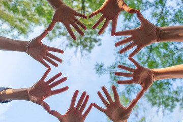 The women's hands of 4 men are joined together by thumbs and little fingers. Teambuilding.