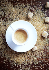 Cup of coffee and brown sugar on wooden background. Top view. 