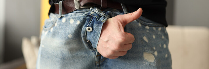 Male hand sticking out of fly of his jeans and showing thumb up close-up. Treatment of sexual...