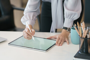 Businesswoman hand working with a stylus pen on a digital tablet with a laptop computer in a modern...