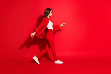 Fototapeta na wymiar Full size profile side photo of lovely pretty girl walk empty space isolated over bright red color background