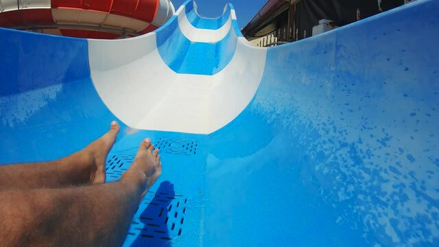 Man having fun on a water slide. Cool people having fun on the water slide in the aqua fun park glides playing happy and water splashes are all over.