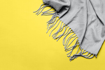 Trending colors of 2021 Ultimate Gray and Illuminating. Grey scarf with tassels on yellow background. Minimal winter or autumn background for your design