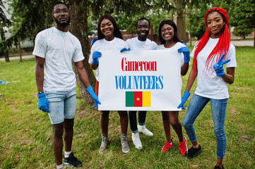 Group of happy african volunteers hold blank with Cameroon flag in park. Africa countries volunteering, charity, people and ecology concept.