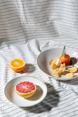 food, healthy eating and fruits concept - close up of mandarin, grapefruit and orange on plates over drapery