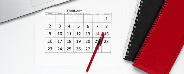 Top view of calendar of February page with pen on it, notepads, and laptop. Template, office concept