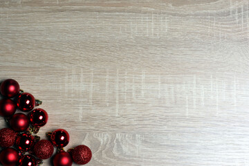 Christmas and New Year template with red balls on light oak wood textured surface with copy space