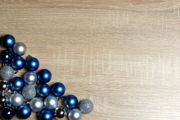 Christmas and New Year composition with blue and silver balls on light oak wood textured surface with copy space