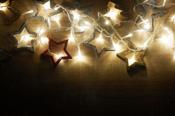 Dark Christmas and New Year frame template from christmas decorations illuminated by a led garland on light oak wood textured surface with copy space