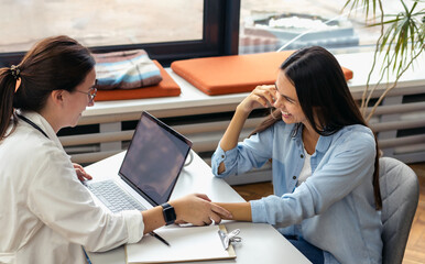 Woman doctor holds patient's hand and writes prescription for medicine.