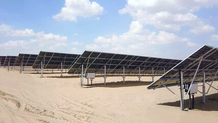 close up of solar power panels in desert with view of distribution board with cloudy sky in background. photovoltaic PV modules in a Solar energy plant farm - 399740674