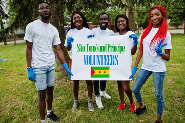 Group of happy african volunteers hold blank with Sao Tome and Principe flag in park. Africa...