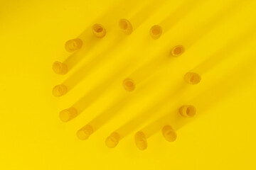 small group of fresh macaroni rigati lined up in a circle on yellow background