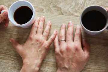 Hände berühren sich zärtlich beim Kaffee trinken