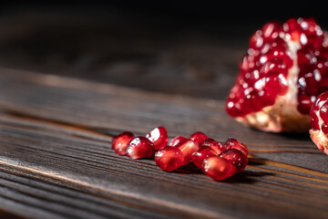 Craked ripe pomegranate on dark wooden background
