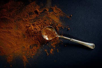 bitter cocoa powder and a silver spoon on a black background