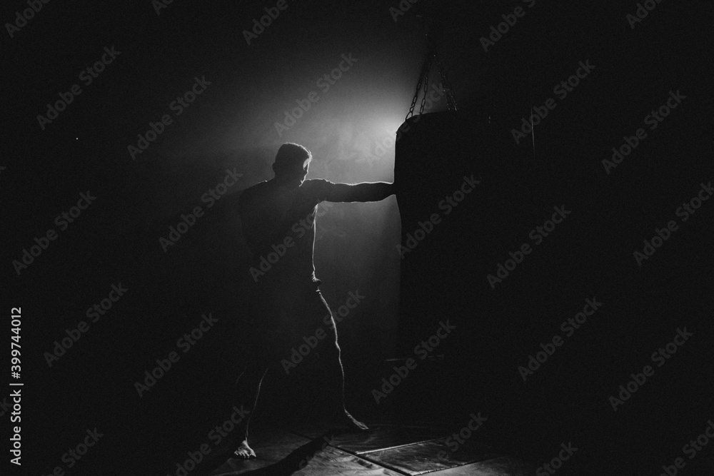 Wall mural fighter striking a blow. professional sport. fighting. strength. fighter in a moody light and grain 