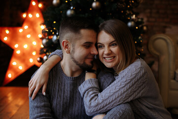 lovers are sitting under a christmas tree with gifts