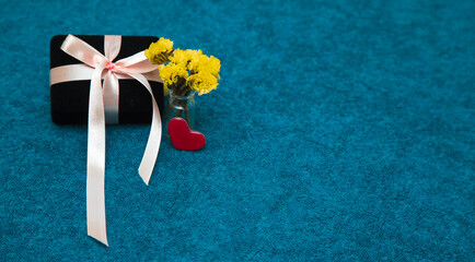 Gift box with ribbon and heart and yellow flowers. Coposy for Valentine's Day