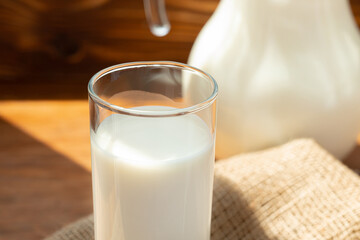 Glass pitcher of milk on old wooden table