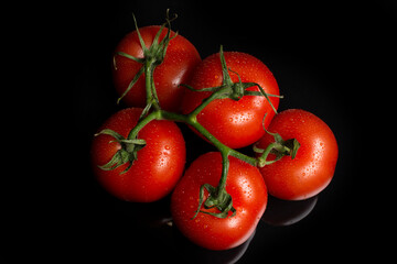 a bunch of large tomatoes with water drops on a black background