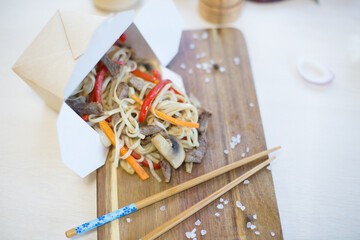 Naklejka na ściany i meble Noodles with vegetables in take-out box on wooden table Healthy food