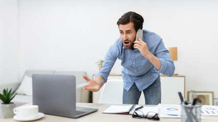 Naklejka premium Angry Businessman Talking On Phone Standing In Office