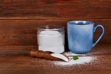 Cup of tea, glass jar and scoop of sorbitol on a wooden background. Sweeteners and diet concept. 