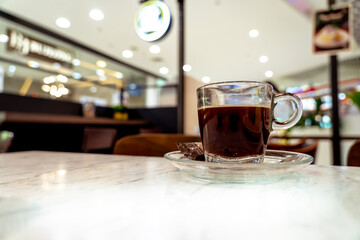 A  hot americano is served at a coffee shop, putting on the wooden table.