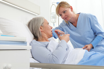 Fototapeta premium nurse gives the pill to the elderly woman patient lying in the hospital room bed, concept of loneliness and old age diseases