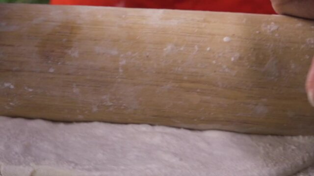 Stretching Pizza dough close up shot from rolling pin moving forward