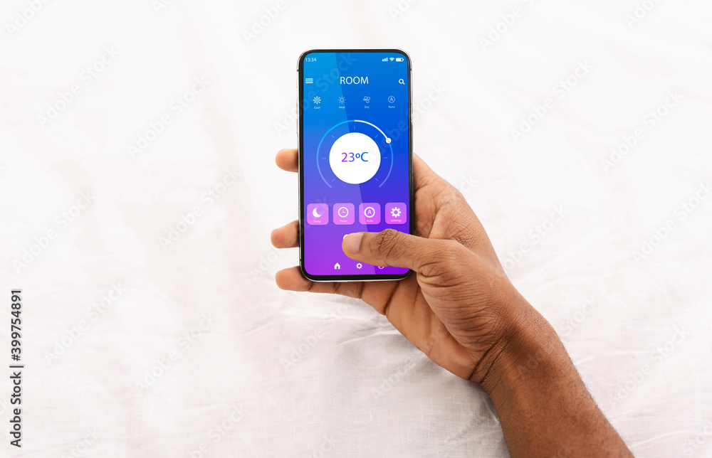 Aufkleber black man holding cellphone with smart home application in bed, regulating temperature, creating coz