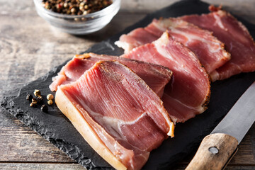 Dried and smoked meat slice on wooden table	