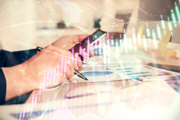 Double exposure of man's hands holding and using a phone and financial graph drawing. Analysis concept.