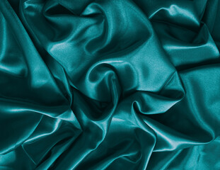 Elegant smooth blue green satin, silk fabric drapes. Luxurious cloth textile with liquid wave. Abstract background or template. Fabric shiny glitter texture. Luxurious blue background.	