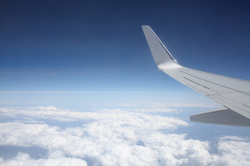 Widok z okna samolotu na chmury i skrzydło - obrazy, fototapety, plakaty