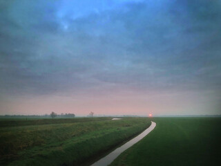 Fototapeta na wymiar Misty sunset. Polder Netherlands. Havelte Drenthe. Ditch. Flat landscape and meadows. Evening. Winter.