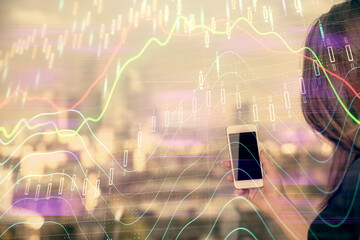 Double exposure of forex chart sketch hologram and woman holding and using a mobile device. Stock market concept.