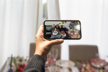 Video call with family on online in christmas time, hand  holding the smartphone, father looking the sons on lockdown. Family and technology concept.