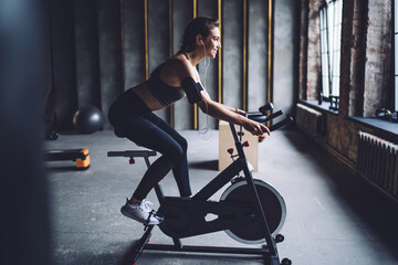 Content sportswoman exercising on cycling machine