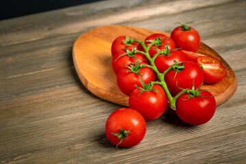 Cherry tomatoes on a branch on a wooden board