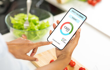 Dieting Concept. Woman eating salad and counting calories with app on smartphone