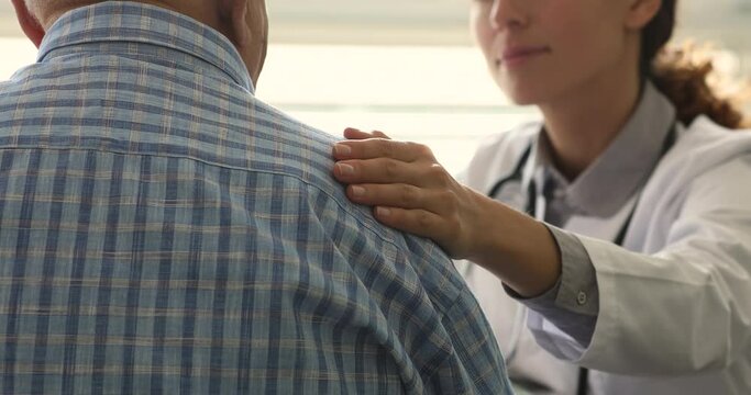 Therapist during pep talk put arm on older 70s male patient shoulder, close up. Eldercare, gerontology, bad news, express empathy, consoling of aged man before course of treatment for disease concept