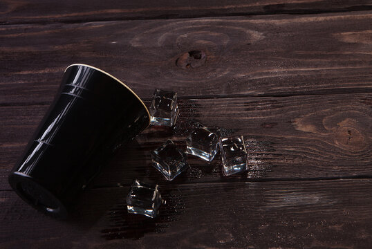 Black Plastic Cup And Ice Cubes On Dark Wooden Background