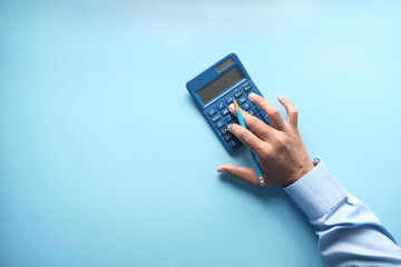 top view of accountant using calculator on blue background 