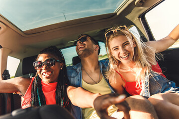 Three best friends enjoying traveling in the car, sitting in rear seat and having lots of fun on a...