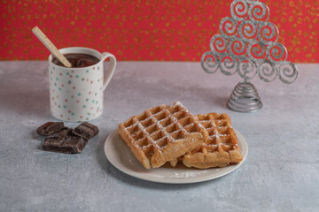 Two homemade waffles with a cup of hot chocolate over a table on christmas.